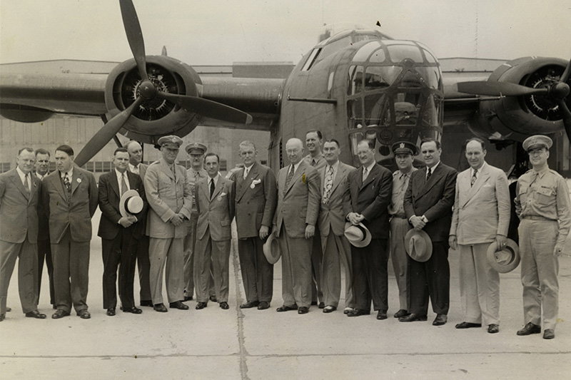 Freedom Team - Then Gen. William Knudsen, center foreground in military uniform, led the U.S. war effort during World War II. To his left is Edsel Ford, president of Ford Motor Co., and to Ford’s left is Charles E. Sorensen, a vice president of Ford who oversaw the automaker’s defense contracts. The group was photographed in August 1942 at Willow Run Airport in Ypsilanti Township. The Danish film crew filming Knuden’s life story, opposite page, gathers at Willow Run Airport in front of a B-25D Mitchell bomber owned and operated by the Yankee Air Museum. // Courtesy of the Detroit Public Library