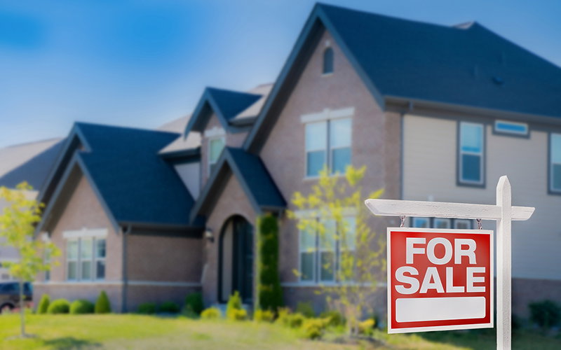 Blurred house with for sale sign in front.