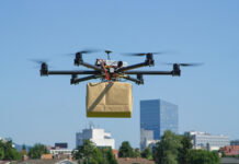 Auto Parts Delivery via Drones Takes Off at Jack Demmer Automotive Group in Wayne UAV drone delivery delivering big brown post package into urban city