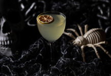 Dedicated Halloween-themed Bars by Black Lagoon Coming to Detroit and Ann Arbor A light green cocktail in a spooky setting, featuring a skull and a spider skeleton.