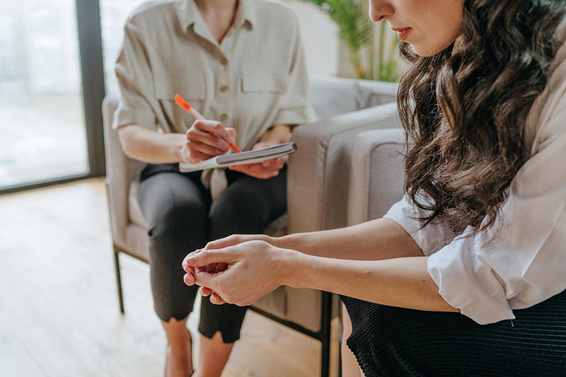 Close-up of young woman talking about her mental health problems to the doctor during counseling.