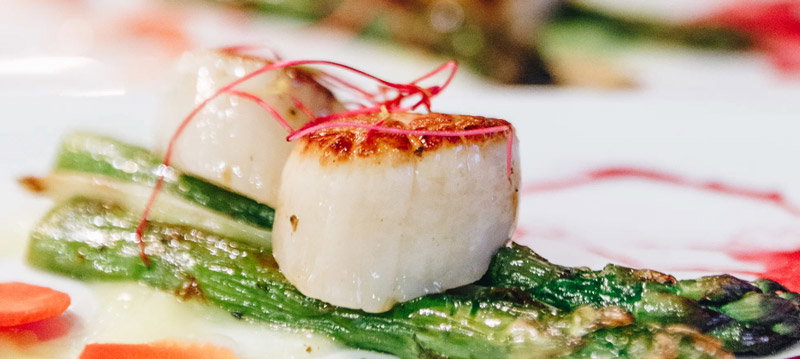 A scallop atop of asparagus.
