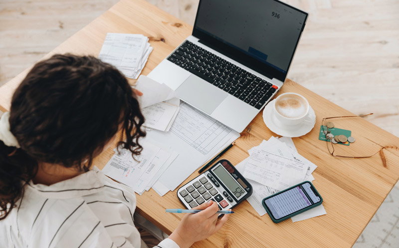 Woman working on her bills with a laptop and a calculator