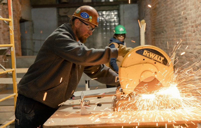 A man using a tool to cut metal.